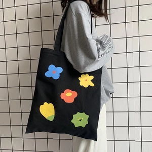 Dettaglio della borsa tote in tela con stampe floreali colorate su fondo nero