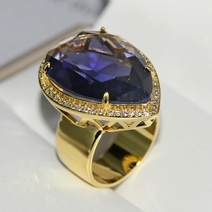 Macro shot of a luxurious gold ring featuring a large pear-cut purple crystal gemstone