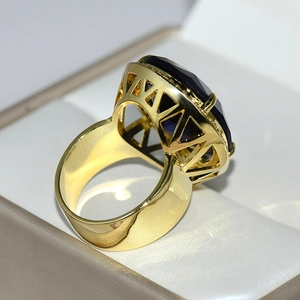 Macro shot of luxury gold ring featuring a large deep blue oval teardrop crystal