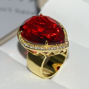 Macro shot of luxury pear-cut red gemstone ring with crystal halo in golden setting