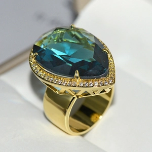 Macro shot of luxury gold ring featuring teardrop blue crystal and pave zircon details