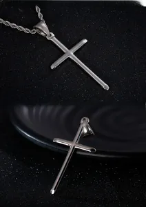 Detailed view of a polished stainless steel cross pendant with a classic rope chain