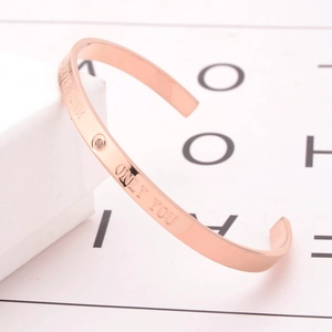 Detail of rose gold C-shaped bracelet featuring Forever Love engraving and small zircon