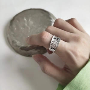 Detail shot of wide 925 silver ring with lava texture worn on the index finger