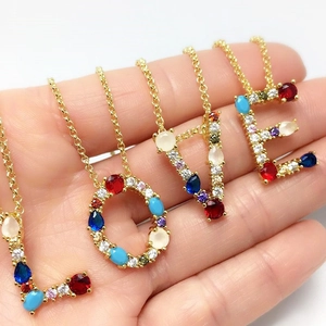 Golden necklace with colorful zircon letter pendants L O V E on a person's palm