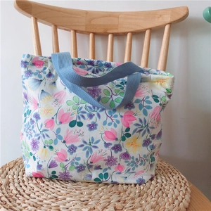 Florale Canvas-Lunchtasche mit bunten Blumenmustern und dunkelblauen Webgriffen