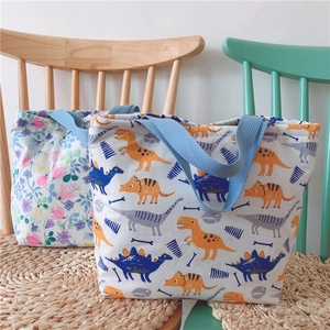 Detailansicht der Canvas-Lunchtaschen mit Blumen- und Dinomuster und blauen Griffen