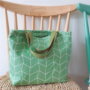 Nahaufnahme einer grünen Canvas-Lunchtasche mit Würfelmuster auf einem Sitzkissen