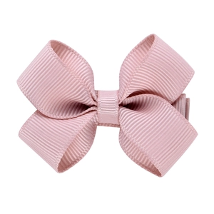Détail de la texture en ruban gros-grain rose et du design du nœud sur la barrette
