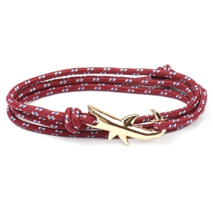 Detail of red white blue woven bracelet featuring a distinctive gold shark-shaped metal clasp