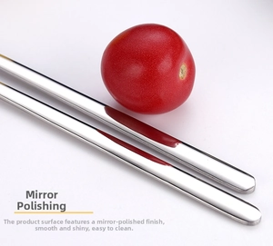 Macro shot of mirror-polished silver stainless steel chopsticks with a red tomato detail