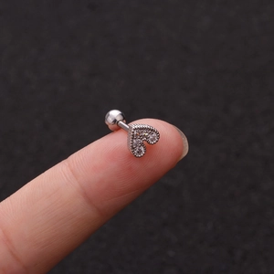 Close-up of a silver heart stud earring with clear zircons held on a fingertip
