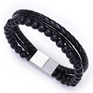 Detail of men's multilayer bracelet featuring black braided leather, lava stone beads, and steel clasp