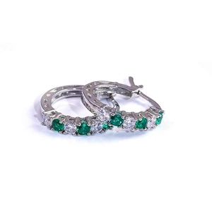 Detail of silver hoop earrings featuring alternating emerald green and white zircons