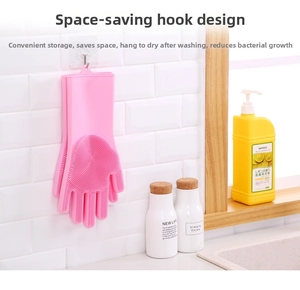 Pink silicone grooming glove with dense bristles hanging on a white tiled kitchen wall