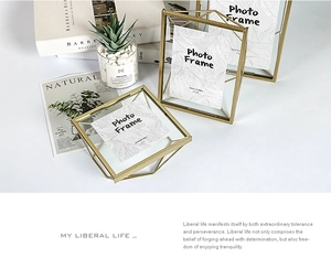 Detail of 4x6 geometric gold metal photo frame with double-sided glass on white desk