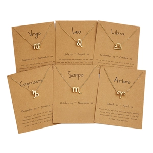 Set of gold zodiac sign necklaces with rhinestone pendants on kraft gift cards