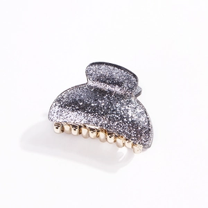 Detail of glitter silver acrylic hair claw clip with golden metal teeth on white background