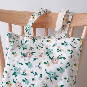 Detail of floral cotton tote bag with small flower pattern hanging on wooden chair