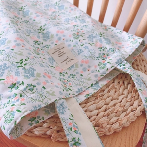 Close-up of floral cotton tote bag with delicate blue and pink blossoms on wood chair