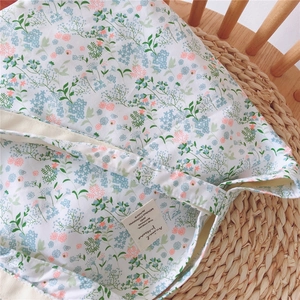 Close-up of floral cotton tote bag with vintage botanical prints on a woven mat