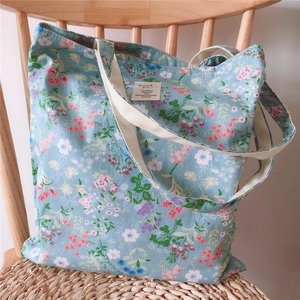 Detail of floral canvas tote bag with pink flowers on blue fabric and soft straps
