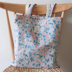 Detail of floral cotton tote bag with blue and pink flower print on a wooden chair
