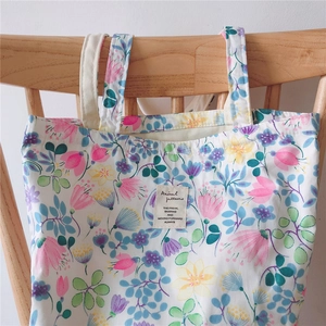 Close-up of floral canvas tote bag featuring pink and yellow flowers on a wooden chair