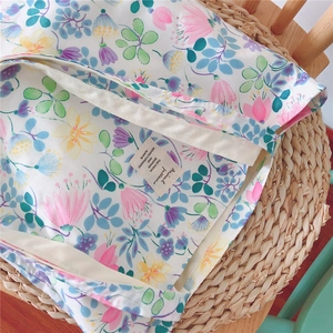 Detail of floral canvas tote bag showing interior label on rustic straw mat