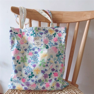 Detail of floral canvas tote bag showing pink flower pattern and woven strap on chair