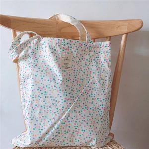 Detail of colorful polka dot cotton tote bag with vintage woven label on a wooden chair