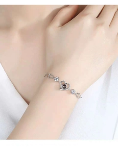 Close-up of heart link bracelet with round zircons and black projection stone pendant