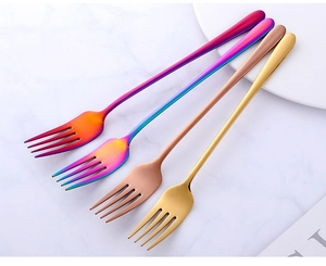 Close-up of rainbow and rose gold stainless steel dinner forks on marble surface