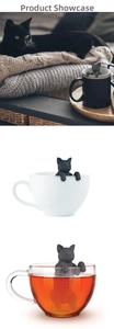 Close-up of black silicone cat tea infuser hanging on cup rim for loose leaf tea