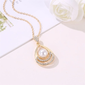 Detailed view of water drop pearl necklace with gold chain and sparkling rhinestones