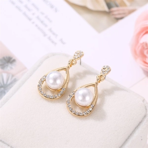 Close-up of pearl drop earrings with rhinestones on a white velvet jewelry box