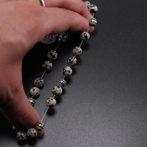 Dalmatian stone beaded necklace with vintage silver lotus pendant held in hand