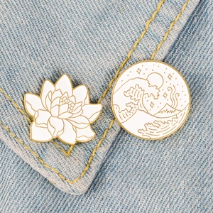 Japanese Ukiyo-e style enamel pins featuring white lotus and ocean wave on denim