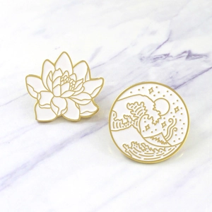 Close-up of retro enamel pins featuring white lotus and Japanese wave art design