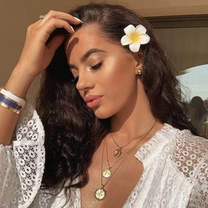 Detail of layered gold jewelry set with shell pendant and bracelets on a female model