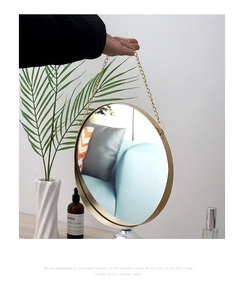 Detail of round gold metal frame mirror with a matching hanging chain for wall decor