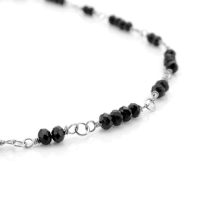 Macro detail of geometric black faceted crystal beads and silver steel chain link