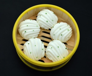 Detail of five realistic steamed flower buns with green spots in a bamboo steamer