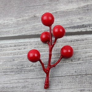 Close-up of artificial red berries branch with glossy finish on grey wood background