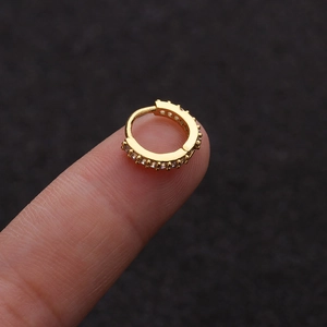 Detailed close-up of a mini gold-plated hoop earring with sparkling zircon stones