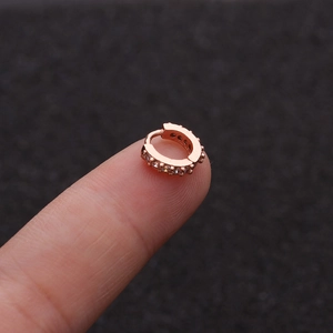 Macro shot of rose gold cubic zirconia hoop earring on fingertip showing size and detail