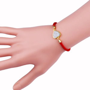 Pulsera trenzada roja minimalista con dije de corazón dorado en la muñeca