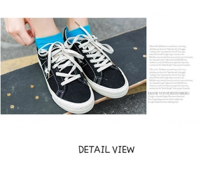 Detail view of cotton socks paired with black star pattern canvas sneakers on a skateboard