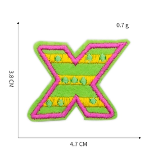 Detailed embroidery texture of pink and yellow letter X patch on neon green base