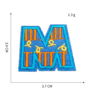 Close-up of letter M embroidery patch showing blue base with orange and yellow stitching